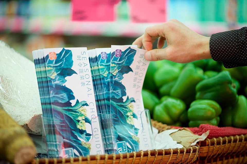 Person's hand picking up a Seasonal Choi Guide at a shop